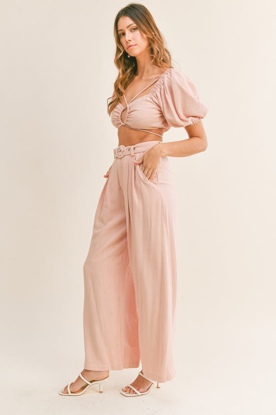 Model wearing a ruched crop top with cutouts and high-waisted belted pants in a soft pastel tone, perfect for brunch or casual outings.

