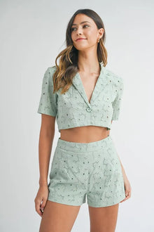 Model wearing mint green eyelet two-piece set with cropped blouse and high-waisted shorts, shown in front view for summer outfit inspiration.