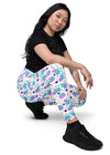 Front view of a model sitting in Cosmic Cats White High-Waisted Leggings. Ideal for yoga or a day out, these leggings feature a playful cosmic cat design with functional pockets.