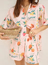 Stylish model in a peach printed two-piece summer set, showing a front pose with the lightweight button-down shirt and coordinating airy skirt.