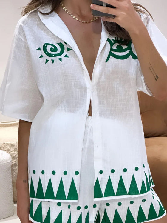  Woman modeling a white button-down printed outfit set with a clean, crisp top and coordinated floral skirt, perfect for light, sunny weather.