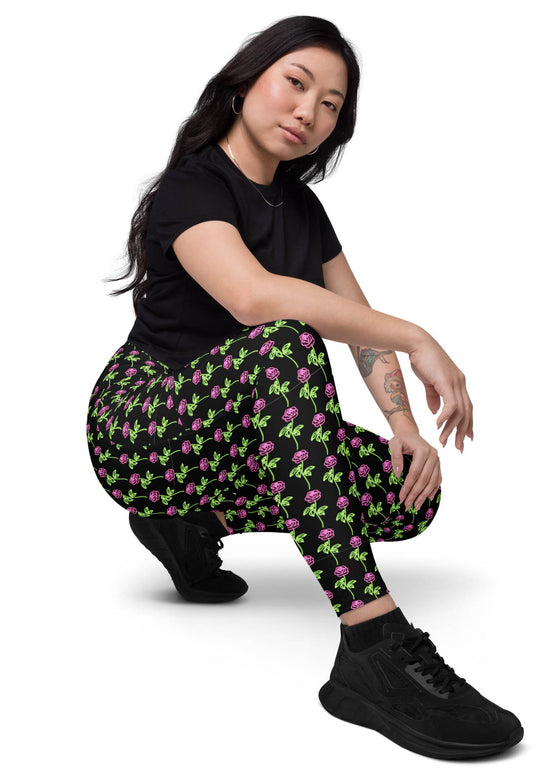 Model sitting and showing the side of neon roses black high-waisted leggings with pockets. Combining comfort, style, and practicality for everyday wear or workouts.