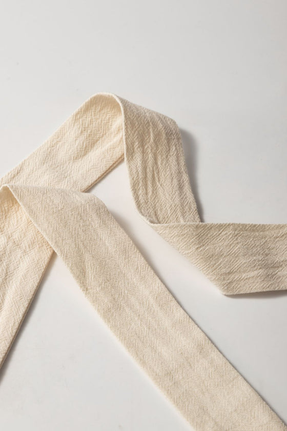 Close-up of tie waist detail on tassel-trimmed neutral beige wrap skirt—adjustable fit adds flair and comfort for versatile, everyday wear.