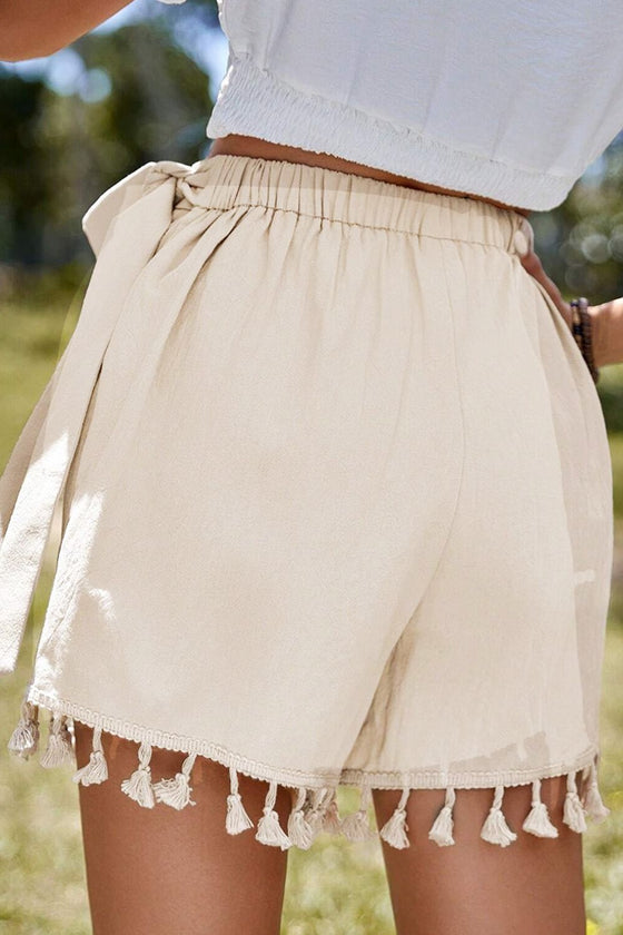 Back close-up of tie waist wrap skirt in neutral beige, highlighting tassel-trimmed hem and elegant drape—perfect for laid-back yet refined fashion.