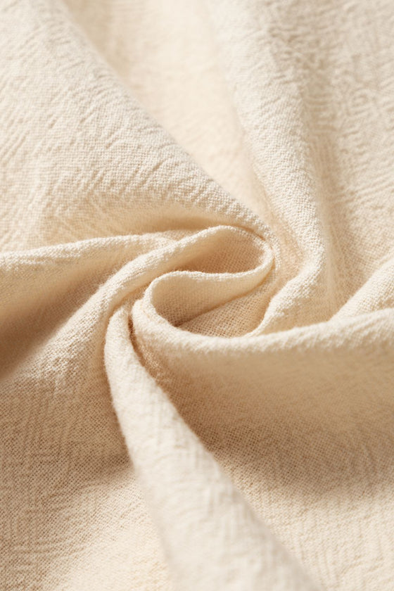 Neutral beige wrap skirt folded flat with visible tassels and tie waist—soft, travel-friendly fabric ideal for packing light and staying stylish.