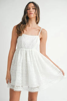  Off white babydoll mini dress with delicate lace overlay and puff sleeves, styled with a flattering front silhouette for a romantic and chic appearance.