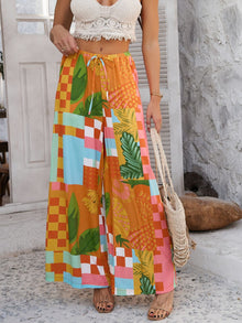  Model wearing stylish orange wide leg pants featuring vibrant multicolor abstract print, drawstring waist for adjustable fit, crafted from soft and breathable lightweight fabric perfect for casual summer outings and relaxed daily wear.

