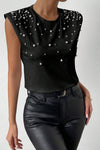 Lifestyle image of a woman wearing the Pearl Detail Round Neck Tank styled with black leather pants for a chic, bold look.