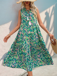  Woman wearing a colorful Perfee Tassel Printed Tie Neck Sleeveless Dress, featuring a boho-inspired tassel detail and vibrant print, perfect for summer.