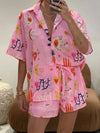 Model wearing a pink button down summer outfit set with a collared shirt and coordinated printed skirt, perfect for sunny brunches or beachside strolls.
