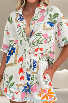  Model wearing a printed two-piece set with a button-up half-sleeve top and drawstring shorts, featuring vibrant floral patterns for summer.