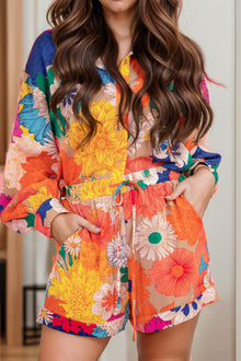  Woman wearing a vibrant floral printed button-up long sleeve top and shorts set, perfect for casual outings or lounging in style.

