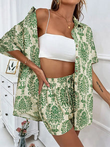  A model wearing a Printed Button Up Top and Shorts Set in a sophisticated green pattern, styled with a white crop top, perfect for casual summer outings.

