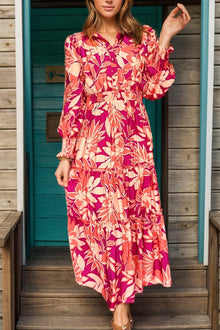  Model wearing a Printed Collared Neck Long Sleeve Maxi Dress with vibrant floral print in pink and coral tones, featuring a tiered design and button-up front.