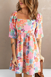  Woman wearing a Printed Half Sleeve Mini Dress featuring a colorful floral pattern, square neckline, and elegant half sleeves. Ideal for casual outings and chic celebrations.