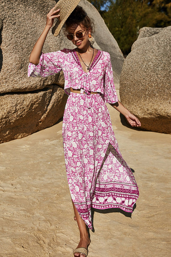 Model wearing a vibrant floral two-piece set with a half-sleeve tie-front top and a high-waist slit skirt, perfect for summer outings and vacations.

