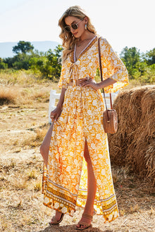  Model wearing a vibrant floral two-piece set with a half-sleeve tie-front top and a high-waist slit skirt, perfect for summer outings and vacations.