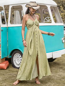  Woman wearing a Printed Halter Neck Maxi Dress featuring a tied neckline, buttoned front, and vibrant green print, styled for a boho-chic look.