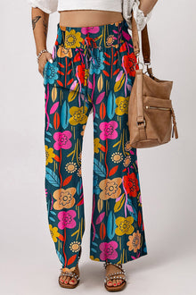  Woman wearing Printed High Waist Wide Leg Pants with vibrant floral design, styled with a crop top and studded sandals.