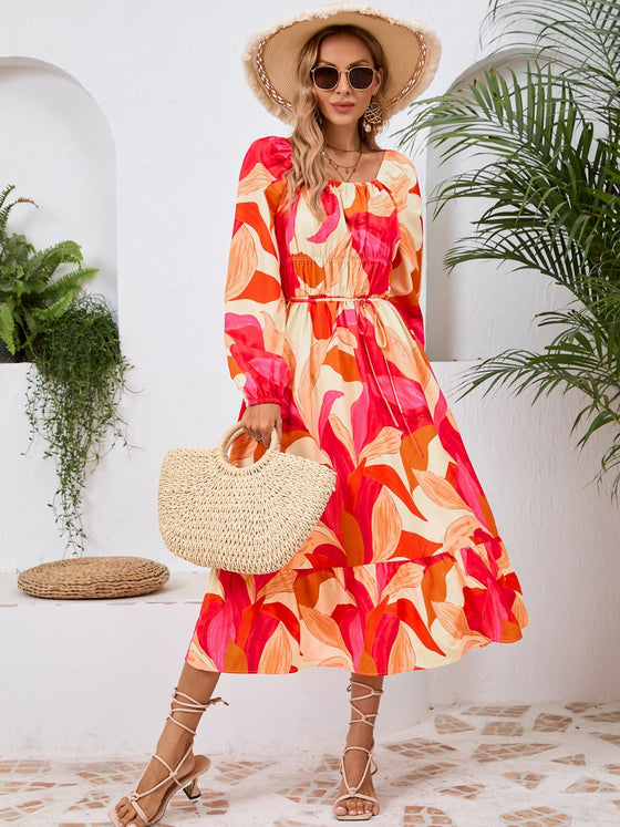 Woman wearing a Printed Long Sleeve Midi Dress featuring a tied waist, off-shoulder neckline, and vibrant print, perfect for casual outings or evening wear.