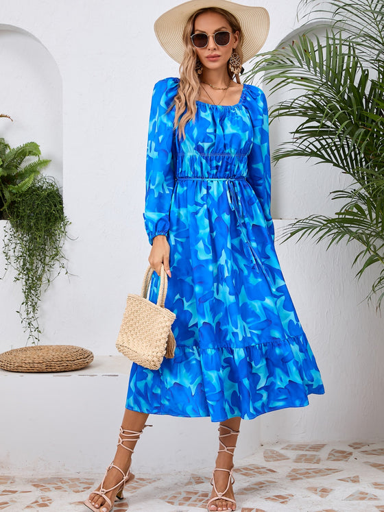 Woman wearing a Printed Long Sleeve Midi Dress featuring a tied waist, off-shoulder neckline, and vibrant print, perfect for casual outings or evening wear.