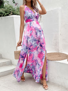  Woman wearing a chic printed sleeveless maxi dress with an open back, halter neck, and thigh-high slit, perfect for summer outings.