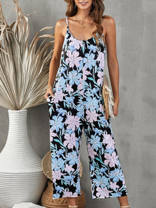  Woman wearing a floral printed spaghetti strap jumpsuit with side pockets, featuring a relaxed wide-leg design, ideal for casual summer outings.