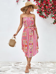  Woman wearing a chic printed strapless midi dress with a tie belt, perfect for summer outings.