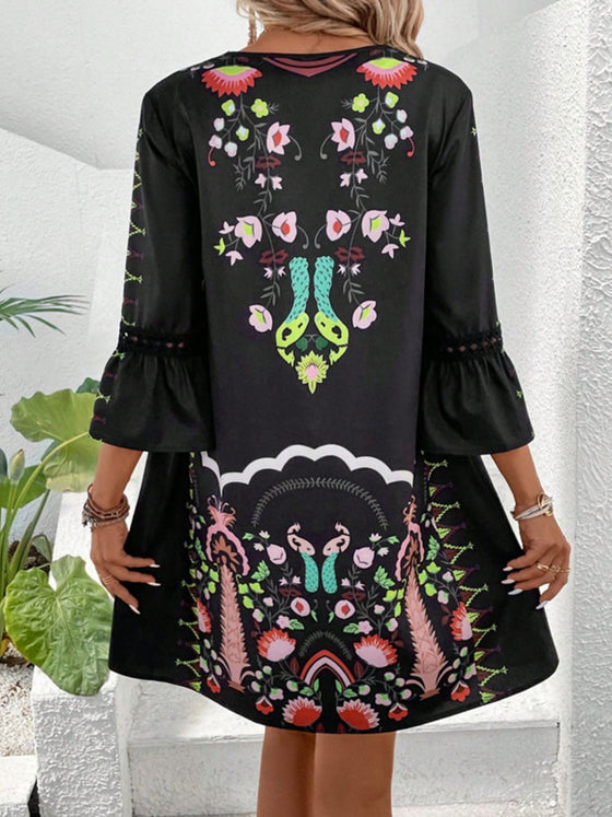 Back view of the black dress taken at a slight angle, showcasing clean seams and the continuation of the print pattern.

