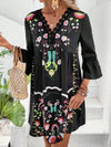 Model in the black printed dress with a centered front view, emphasizing the contrasting floral design and elegant neckline.

