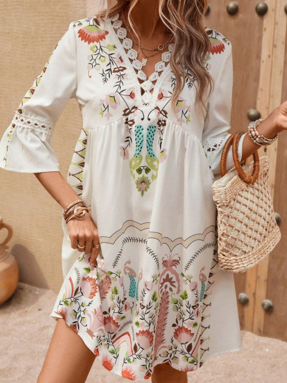 Model wearing the tan printed dress from the front, highlighting the graceful fall of the three-quarter sleeves and the relaxed midi silhouette.

