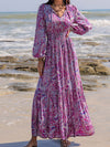 Woman styled in the Printed Tie Neck Maxi Dress at the beach, paired with a straw hat and accessories for a boho-chic look.