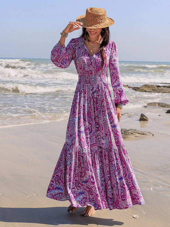 Woman styled in the Printed Tie Neck Maxi Dress at the beach, paired with a straw hat and accessories for a boho-chic look.