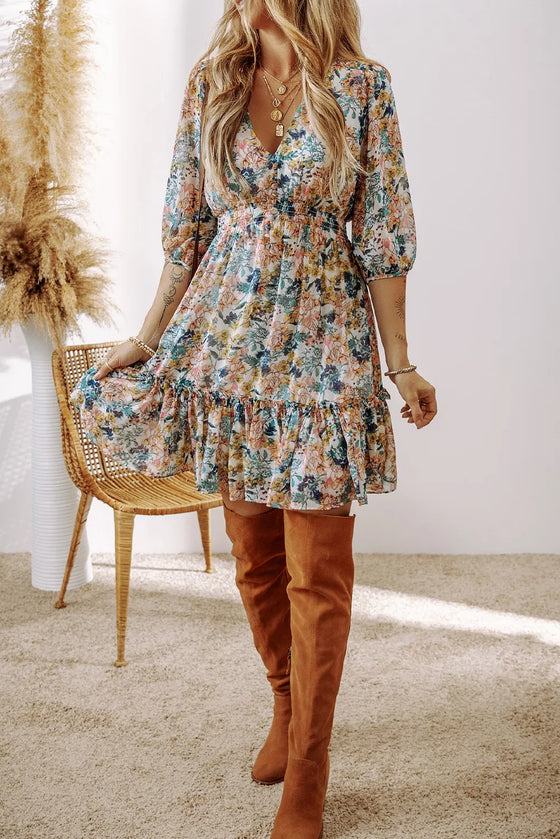 Woman wearing a Printed V-Neck Half Sleeve Dress with a floral pattern, V-neckline, and ruffled hem, paired with brown accessories for a chic look.

