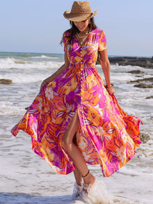  Woman wearing a vibrant printed V-neck short sleeve midi dress with a button-down front and a slit design, perfect for summer beach outings.

