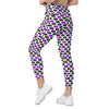 Model walking in white leggings with pop-art lips print in purple and black. High waist compression leggings for women with pockets and sculpted fit.
