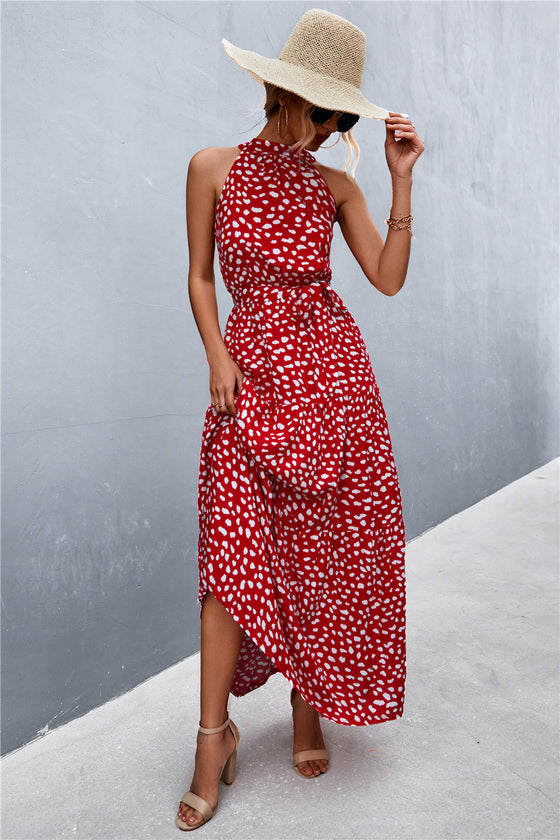 Front view of red printed tie waist maxi dress with bold, bright floral-inspired details—standout style for outdoor and vacation settings.