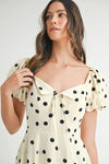  Zoomed-in front detail of cream polka dot midi dress featuring structured puff sleeves and romantic tailoring.


