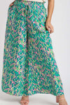 Model stands facing forward in the printed green pants, showing the fluid leg structure and high-waisted comfort fit.

