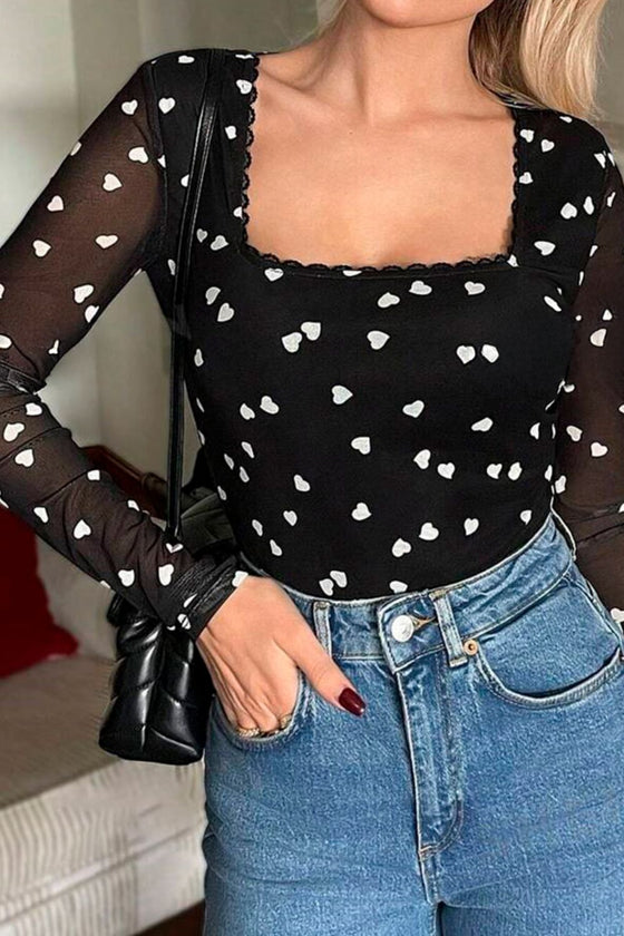 Model styled in the full outfit front view, showcasing the bodysuit’s elevated neckline, sculpted waist fit, and dainty yet daring mesh hearts.

