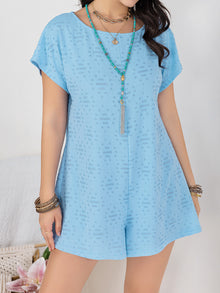  Model wearing a light blue round neck short sleeve romper with a buttoned front and relaxed fit, styled with casual accessories for a chic summer look.

