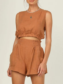  Woman wearing a matching set of sleeveless top and high-waist shorts in a neutral tone. Perfect for casual outings or relaxed days.

