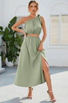 Woman wearing a ruched one-shoulder top paired with a high-waist slit skirt in a sage green tone. Perfect for elegant gatherings or garden parties.

