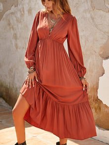  A woman wearing a Ruched V-Neck Long Sleeve Midi Dress with a ruffled hem, styled with boho jewelry and boots, perfect for casual or formal wear.

