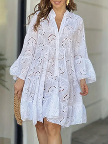  Woman wearing a white eyelet mini dress with a notched neckline, tiered ruffle hem, and long sleeves, perfect for casual or daytime events.

