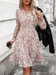  Model wearing a ruffle hem floral surplice long sleeve dress with a cinched waist, styled with a leather jacket and coffee cup, perfect for casual and elegant occasions.

