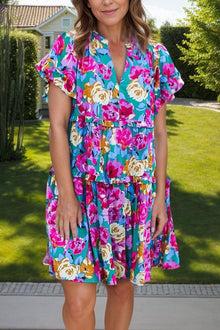  Woman wearing a vibrant Ruffled Printed Notched Short Sleeve Mini Dress with a floral design, perfect for casual summer outings.