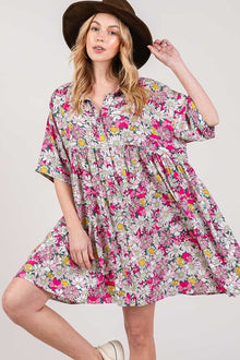  Woman wearing the SAGE + FIG Floral Button Down Mini Shirt Dress featuring a charming floral print, ruched details, and a button-down front for a versatile style.