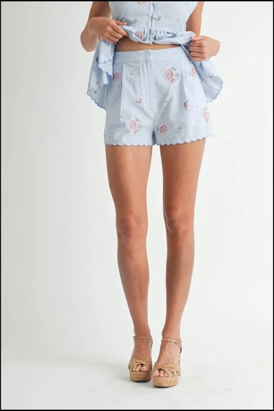Close-up front view of the skirt in the blue floral two-piece set, showing the scallop detail and soft pleats.
