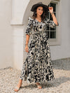 Woman styled in the Smocked Printed Tie Neck Maxi Dress, accessorized with gold jewelry, perfect for formal events.